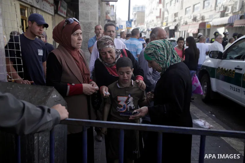 Palestinians wait behind an Israeli security forces barrier and prevented from accessing Jerusalem's Old City as Ultra-nationalist Israelis take part in the "flag march" through Damascus Gate in east Jerusalem on May 28,...