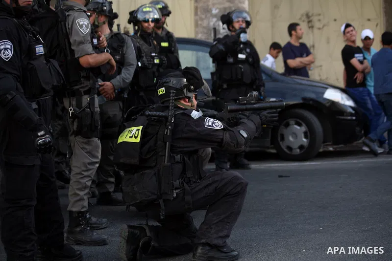 An Israeli border guard fires tear gas towards Palestinians as Ultra-nationalist Israelis take part in the "flag march" through Damascus Gate in east Jerusalem on May 28, 2014 celebrating the anniversary of its capture i...