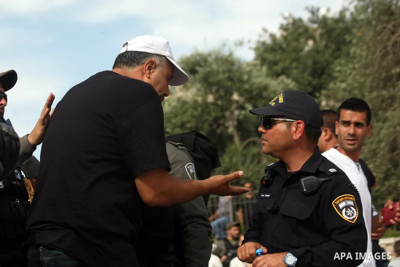 Palestinians wait behind an Israeli security forces barrier and prevented from accessing Jerusalem's Old City as Ultra-nationalist Israelis take part in the "flag march" through Damascus Gate in east Jerusalem on May 28,...