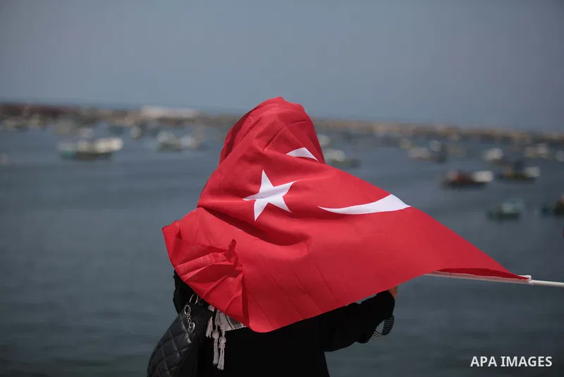 A Palestinian woman holds a Turkish flag as activists ride a boat during a rally ahead of the 4th anniversary of the Mavi Marmara Gaza flotilla incident, at the seaport of Gaza City May 29, 2014. Nine activists, eight Tu...