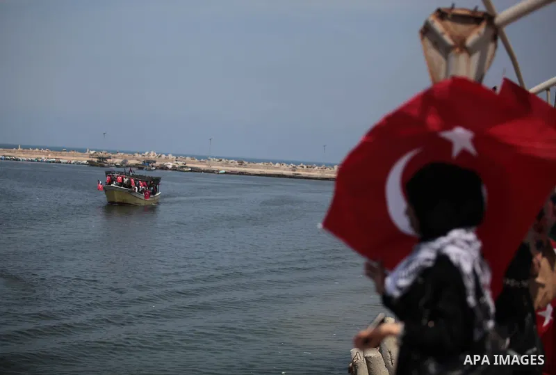 A Palestinian woman holds a Turkish flag as activists ride a boat during a rally ahead of the 4th anniversary of the Mavi Marmara Gaza flotilla incident, at the seaport of Gaza City May 29, 2014. Nine activists, eight Tu...