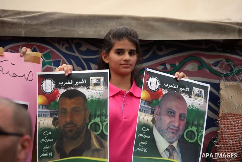 A Palestinian girl holds pictures for the Palestinian prisoners during a protest, in the East Jerusalem neighborhood of Silwan on May 29, 2014. It was about 120 Palestinians imprisoned without trial in Israel on an open...