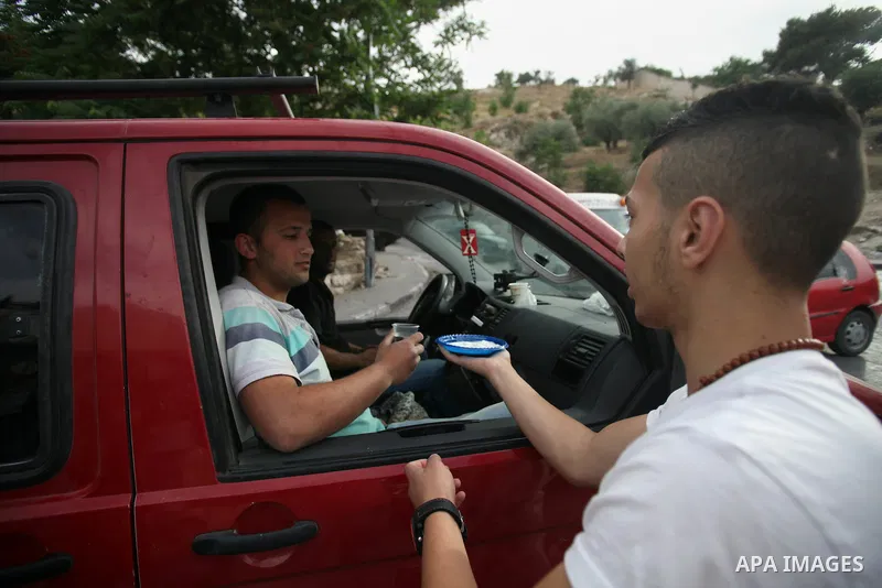 A Palestinian youth distributes water and salt during a protest to solidarity with Palestinian prisoners, in the East Jerusalem neighborhood of Silwan on May 29, 2014. It was about 120 Palestinians imprisoned without tri...
