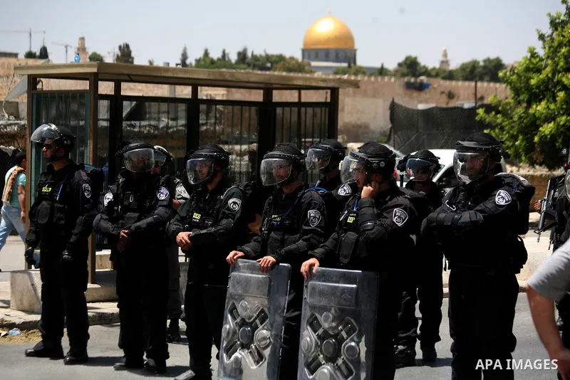 Israeli riot police stand guard as Palestinian muslim worshipers attend the Friday prayers in the East Jerusalem neighbourhood of Ras al-Amud after being refused entry into the Al-Aqsa compound in Jerusalem, 30 May 2014....
