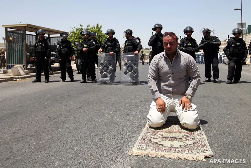 A Palestinian Muslim worshiper attends the Friday prayers in the East Jerusalem neighbourhood of Ras al-Amud after being refused entry into the Al-Aqsa compound in Jerusalem, 30 May 2014. The Israeli police restricted th...