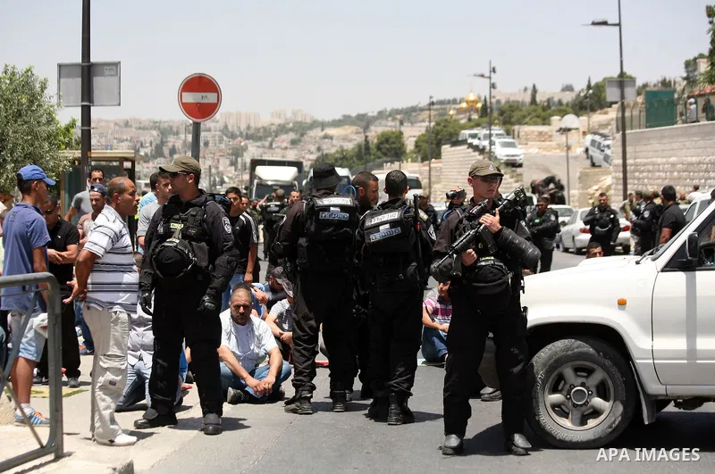 Israeli riot police stand guard as Palestinian muslim worshipers attend the Friday prayers in the East Jerusalem neighbourhood of Ras al-Amud after being refused entry into the Al-Aqsa compound in Jerusalem, 30 May 2014....