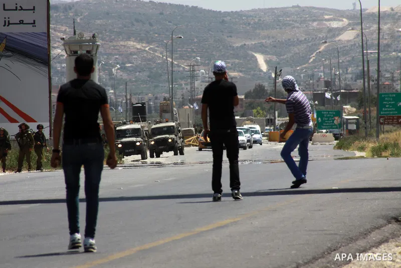 Palestinian protesters throw stones at Israeli security forces during clashes at Huwara checkpoint near the West Bank city of Nablus, May 30, 2014. Photo by Nedal Eshtayah