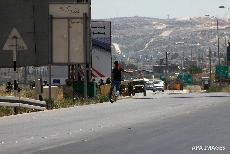 A Palestinian protester throws stones at Israeli security forces during clashes at Huwara checkpoint near the West Bank city of Nablus, May 30, 2014. Photo by Nedal Eshtayah
