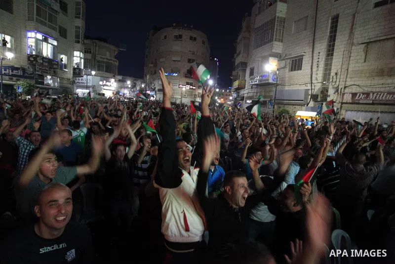 Palestinians celebrate in the West Bank city of Ramallah on May 30, 2014, after Palestine qualified for their maiden Asian Cup appearance with a 1-0 win over injury-hit Philippines in the final of the AFC Challenge Cup i...