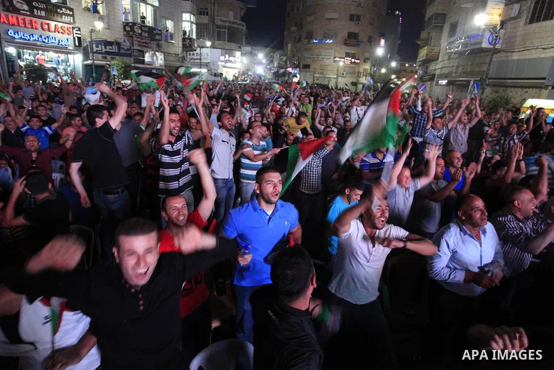 Palestinians celebrate in the West Bank city of Ramallah on May 30, 2014, after Palestine qualified for their maiden Asian Cup appearance with a 1-0 win over injury-hit Philippines in the final of the AFC Challenge Cup i...