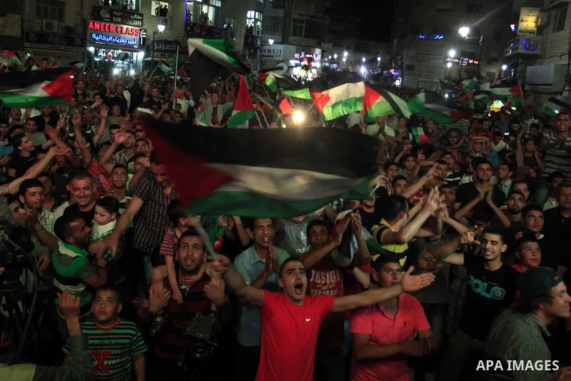 Palestinians celebrate in the West Bank city of Ramallah on May 30, 2014, after Palestine qualified for their maiden Asian Cup appearance with a 1-0 win over injury-hit Philippines in the final of the AFC Challenge Cup i...