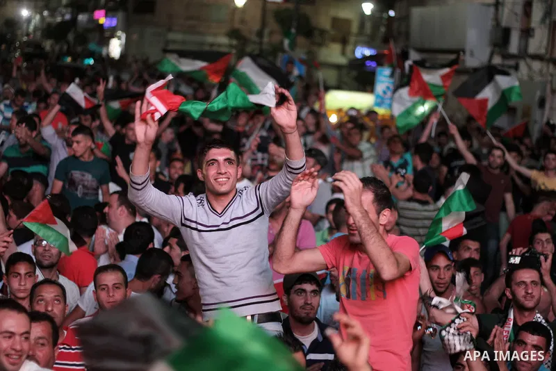 Palestinians celebrate in the West Bank city of Ramallah on May 30, 2014, after Palestine qualified for their maiden Asian Cup appearance with a 1-0 win over injury-hit Philippines in the final of the AFC Challenge Cup i...