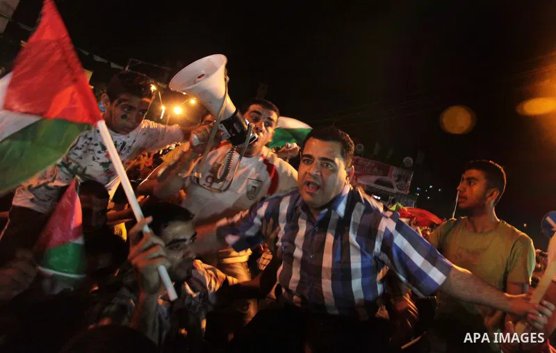 Palestinians celebrate in Gaza City on May 30, 2014, after Palestine qualified for their maiden Asian Cup appearance with a 1-0 win over injury-hit Philippines in the final of the AFC Challenge Cup in Maldives. Photo by...