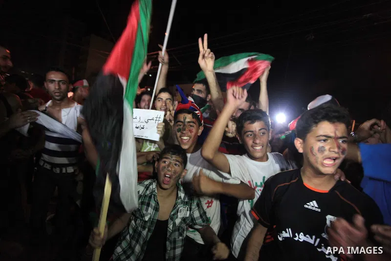 Palestinians celebrate in Gaza City on May 30, 2014, after Palestine qualified for their maiden Asian Cup appearance with a 1-0 win over injury-hit Philippines in the final of the AFC Challenge Cup in Maldives. Photo by...