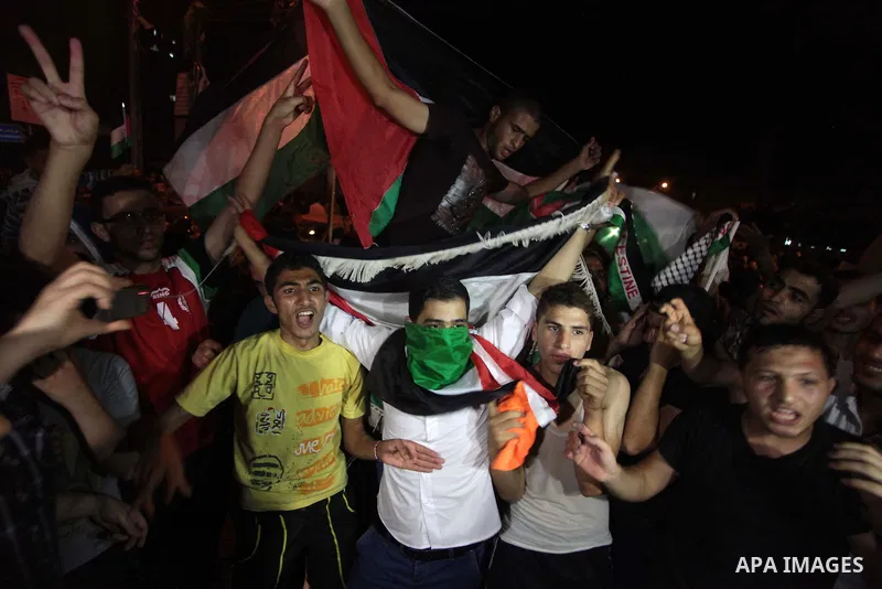 Palestinians celebrate in Gaza City on May 30, 2014, after Palestine qualified for their maiden Asian Cup appearance with a 1-0 win over injury-hit Philippines in the final of the AFC Challenge Cup in Maldives. Photo by...