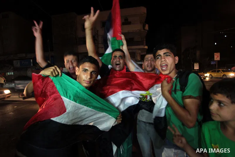 Palestinians celebrate in Gaza City on May 30, 2014, after Palestine qualified for their maiden Asian Cup appearance with a 1-0 win over injury-hit Philippines in the final of the AFC Challenge Cup in Maldives. Photo by...