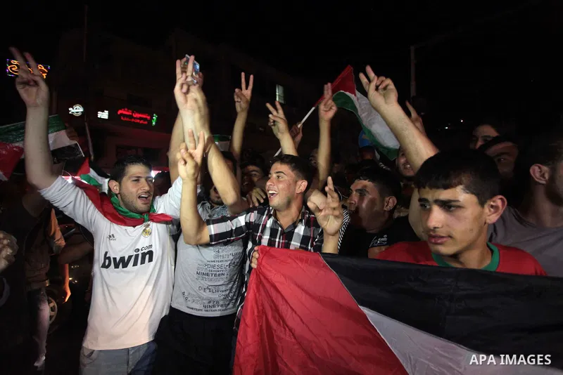 Palestinians celebrate in Gaza City on May 30, 2014, after Palestine qualified for their maiden Asian Cup appearance with a 1-0 win over injury-hit Philippines in the final of the AFC Challenge Cup in Maldives. Photo by...