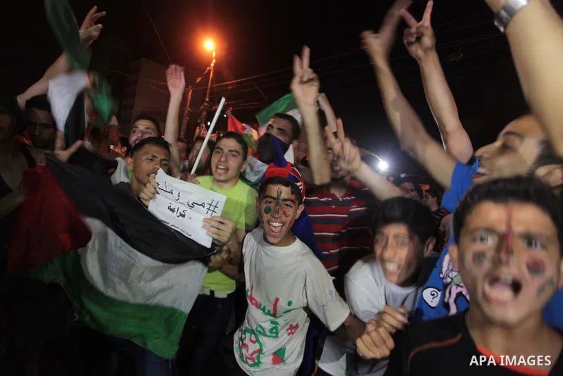 Palestinians celebrate in Gaza City on May 30, 2014, after Palestine qualified for their maiden Asian Cup appearance with a 1-0 win over injury-hit Philippines in the final of the AFC Challenge Cup in Maldives. Photo by...