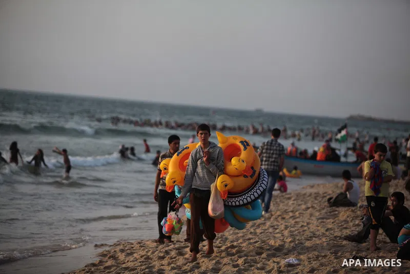 A Palestinian man sells games in the Mediterranean Sea at sunset, in Gaza City, on May 30, 2014. Gaza residents ran to the beach to cool off during the hot weather, as high temperatures hit the city. Photo by Ashraf Amra