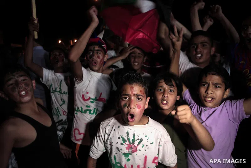Palestinians celebrate in Gaza City on May 30, 2014, after Palestine qualified for their maiden Asian Cup appearance with a 1-0 win over injury-hit Philippines in the final of the AFC Challenge Cup in Maldives. Photo by...