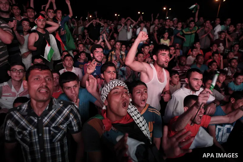 Palestinians celebrate in Gaza City on May 30, 2014, after Palestine qualified for their maiden Asian Cup appearance with a 1-0 win over injury-hit Philippines in the final of the AFC Challenge Cup in Maldives. Photo by...