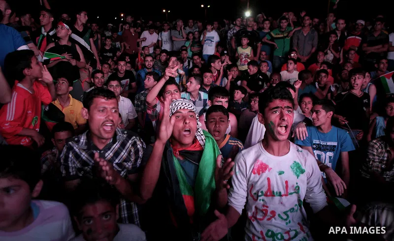 Palestinians celebrate in Gaza City on May 30, 2014, after Palestine qualified for their maiden Asian Cup appearance with a 1-0 win over injury-hit Philippines in the final of the AFC Challenge Cup in Maldives. Photo by...
