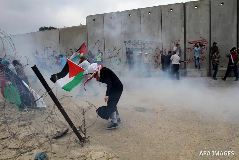 Palestinian protesters wave Palestinian flags in front of a cloud of tear gas during clashes with Israeli forces near the West Bank city of Tulkarem, 31 May 2014. Reportedly dozens of Palestinians were injured during cla...
