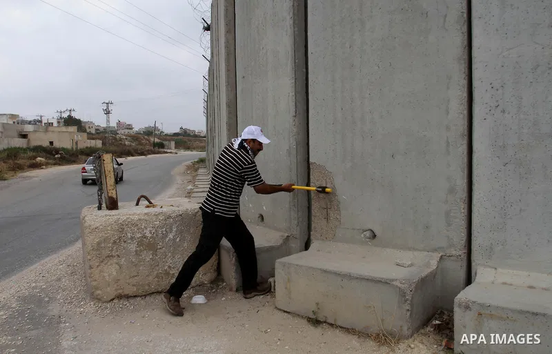 A Palestinian protester uses sledgehammers to break parts from a concrete segment of a separation wall in the West Bank city of Tulkarem, 31 May 2014. Reportedly dozens of Palestinians were injured during clashes with Is...