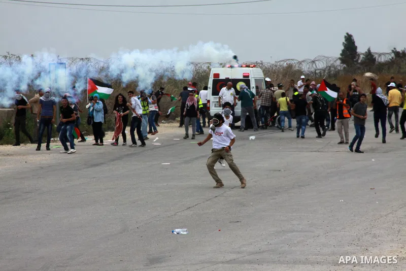 Palestinian protesters wave Palestinian flags in front of a cloud of tear gas during clashes with Israeli forces near the West Bank city of Tulkarem, 31 May 2014. Reportedly dozens of Palestinians were injured during cla...