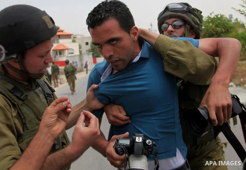 Israeli soldiers detain a photographer during a protest in support of Palestinian prisoners on hunger strike in Israeli jails at the al-Aroub Palestinian refugee camp, just north the West Bank town of Hebron on May 31, 2...
