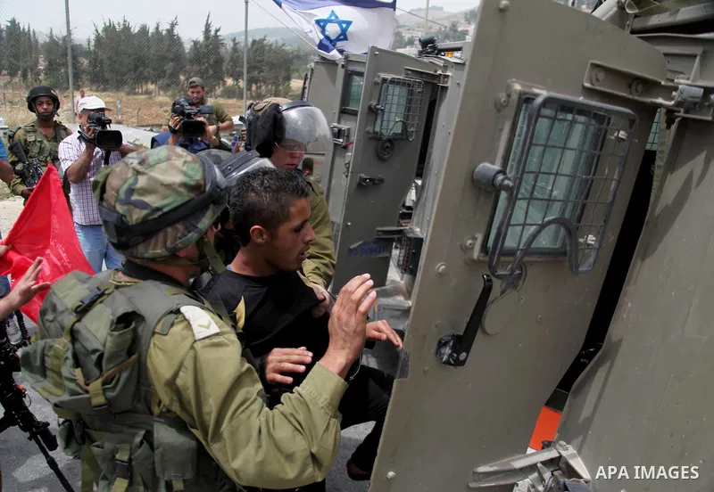 Israeli soldiers detain a Palestinian boy during a protest in support of Palestinian prisoners on hunger strike in Israeli jails at the al-Aroub Palestinian refugee camp, just north the West Bank town of Hebron on May 31...