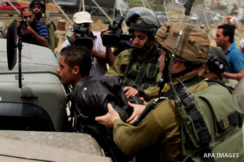 Israeli soldiers detain a Palestinian boy during a protest in support of Palestinian prisoners on hunger strike in Israeli jails at the al-Aroub Palestinian refugee camp, just north the West Bank town of Hebron on May 31...