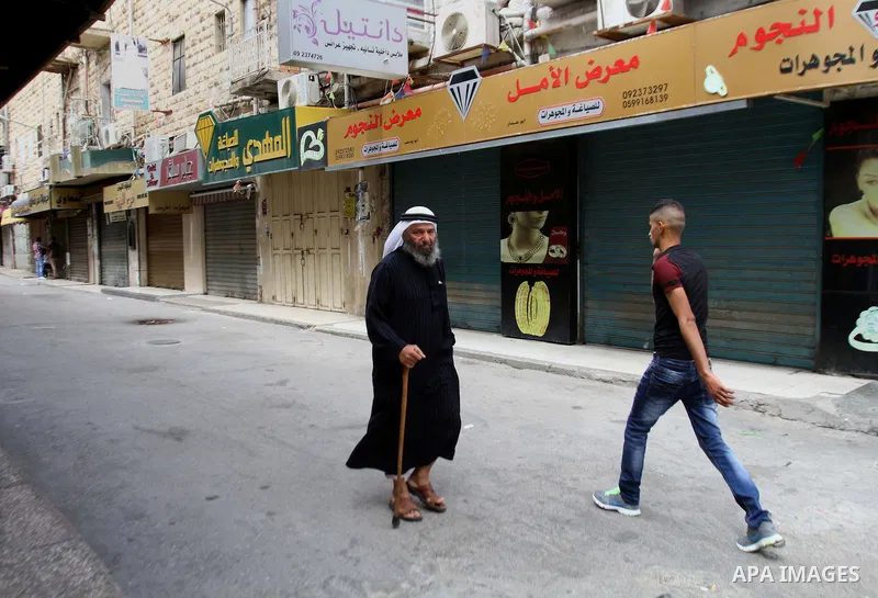 Palestinians walk past a closed shop during a strike to solidarity with Palestinian prisoners on hunger strike held in Israeli jails, in the West Bank city of Nablus on June 1, 2014. Photo by Nedal Eshtayah