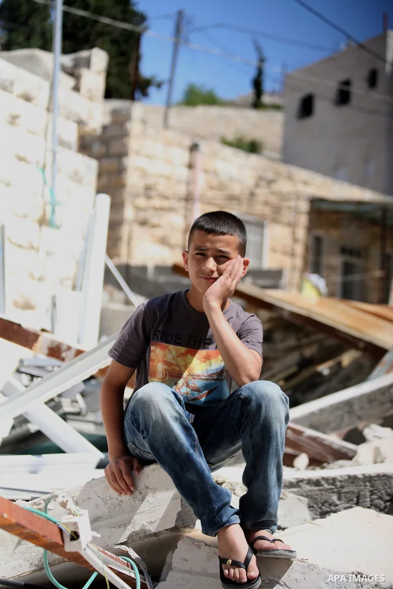 A Palestinian boy sits on the belongings following demolished their sheds by Israeli bulldozers, in al-Tour neighborhood, east Jerusalem on June 02, 2014. Israel destroyed more than 500 Palestinian properties in the West...