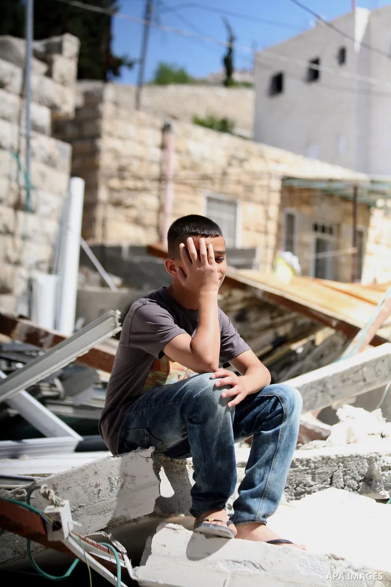 A Palestinian boy sits on the belongings following demolished their sheds by Israeli bulldozers, in al-Tour neighborhood, east Jerusalem on June 02, 2014. Israel destroyed more than 500 Palestinian properties in the West...