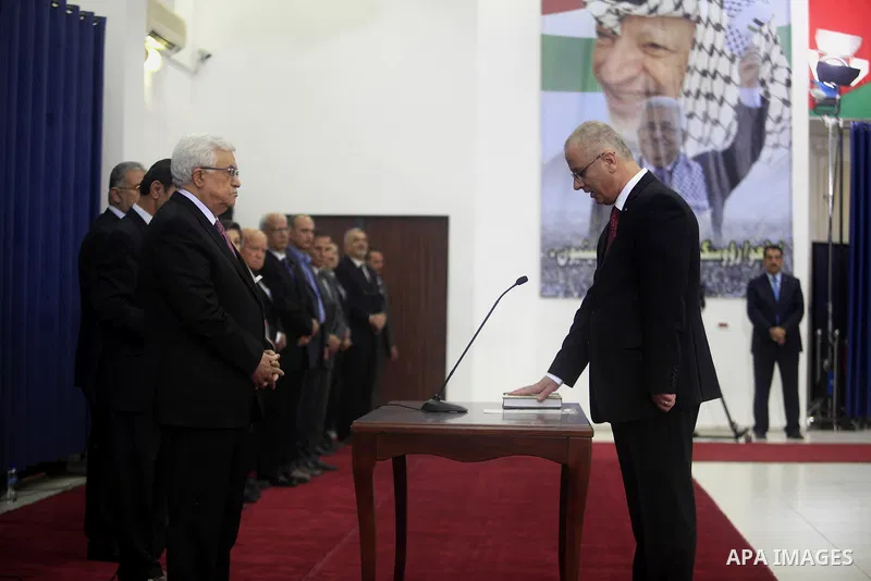 Palestinian Prime Minister Rami Hamdallah (R) is sworn in along with the new Palestinian unity government in the presence of Palestinian president Mahmud Abbas (L) in the West Bank city of Ramallah June 2, 2014. Abbas ha...