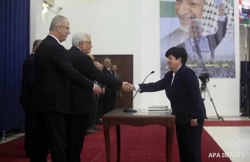 Palestinian Minister of Education and Higher Education, Khawla Shakhshir (R), is sworn in along with the new Palestinian unity government in the presence of Palestinian president Mahmud Abbas (L) in the West Bank city of...