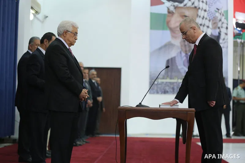Palestinian Prime Minister Rami Hamdallah (R) is sworn in along with the new Palestinian unity government in the presence of Palestinian president Mahmud Abbas (L) in the West Bank city of Ramallah June 2, 2014. Abbas ha...