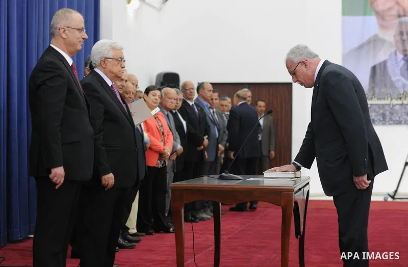 Palestinian Foreign Minister Riyad Al-Maliki (R) is sworn in along with the new Palestinian unity government in the presence of Palestinian president Mahmud Abbas (2nd-L) and Prime Minister Rami Hamdallah (L) in the West...