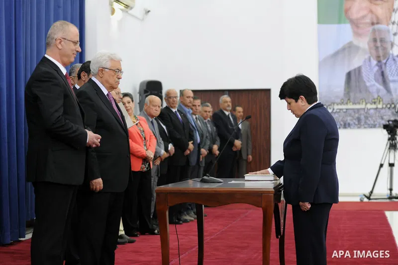Palestinian Minister of Education and Higher Education, Khawla Shakhshir (R), is sworn in along with the new Palestinian unity government in the presence of Palestinian president Mahmud Abbas (L) in the West Bank city of...