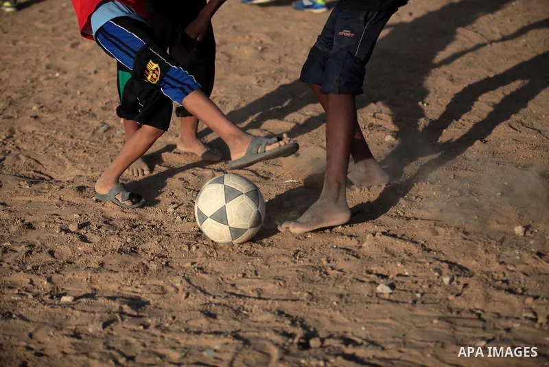 A photo taken on May 26, 2014, shows Palestinian children play football outside their homes, in Deir al-Balah in the central of Gaza Strip. Palestinians share a billion or more people around the globe the feeling of anti...