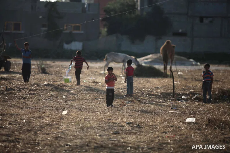 A photo taken on May 26, 2014, shows Palestinian children watch their relatives as they play football outside their homes, in Deir al-Balah in the central of Gaza Strip. Palestinians share a billion or more people around...