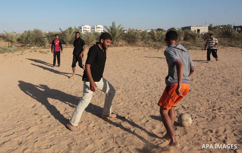 A photo taken on May 26, 2014, shows Palestinian children play football outside their homes, in Deir al-Balah in the central of Gaza Strip. Palestinians share a billion or more people around the globe the feeling of anti...