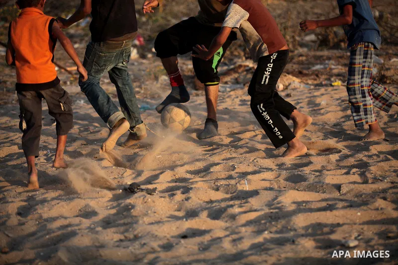 A photo taken on May 26, 2014, shows Palestinian children play football outside their homes, in Deir al-Balah in the central of Gaza Strip. Palestinians share a billion or more people around the globe the feeling of anti...