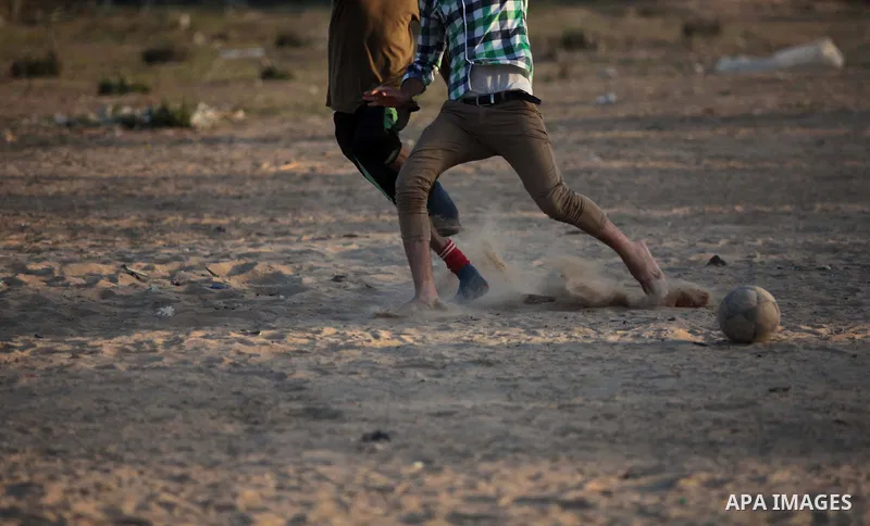 A photo taken on May 26, 2014, shows Palestinian children play football outside their homes, in Deir al-Balah in the central of Gaza Strip. Palestinians share a billion or more people around the globe the feeling of anti...