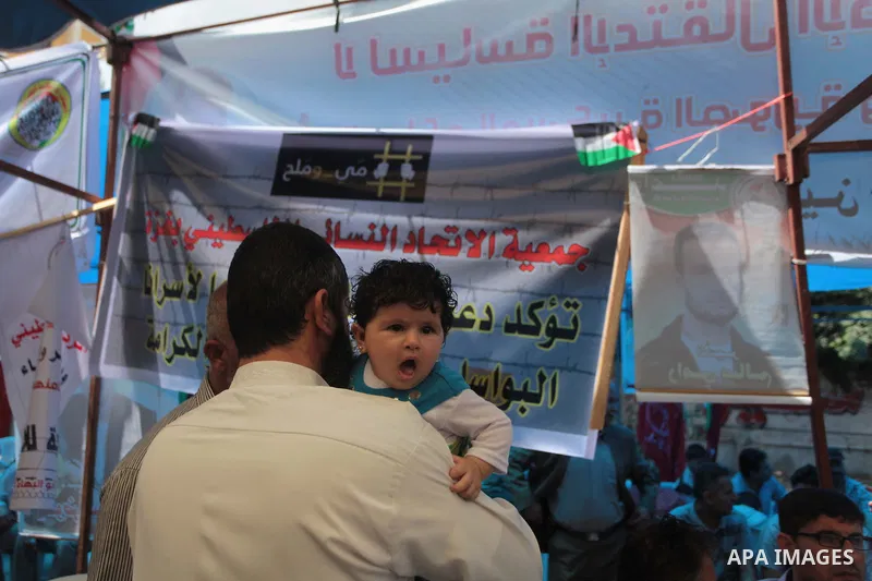 A Palestinian man holds his son as he takes part a protest to solidarity with Palestinian prisoners held in Israeli jails, in front of Red cross office Gaza city, on June 03, 2014. It was about 120 Palestinians imprisone...