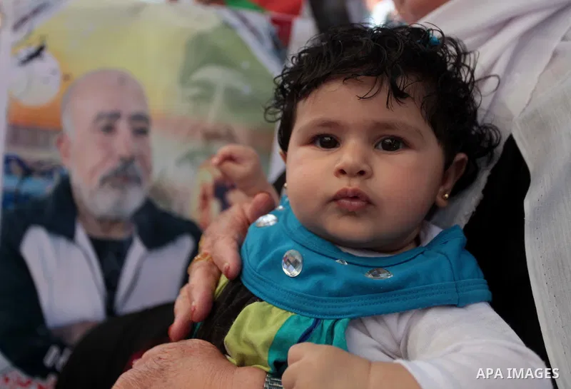 A Palestinian woman holds her son as she takes part a protest to solidarity with Palestinian prisoners held in Israeli jails, in front of Red cross office Gaza city, on June 03, 2014. It was about 120 Palestinians impris...