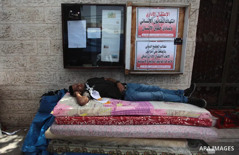 A Palestinian man sleeps during a protest to solidarity with Palestinian prisoners held in Israeli jails, in front of Red cross office Gaza city, on June 03, 2014. It was about 120 Palestinians imprisoned without trial i...