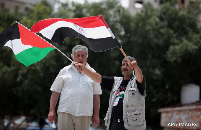 A Palestinian man holds a Palestinian and an Egyptian flag during a celebrate the announcement of the unity government and former Army chief Abdel Fattah al-Sisi winning the presidential election, in Gaza city on June 03...