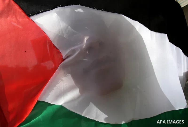 A Palestinian boy who participates in a summer camp organized by Hamas, covers his face with a national flag as others parade the streets during a rally to show solidarity with Palestinian prisoners held in Israeli jails...